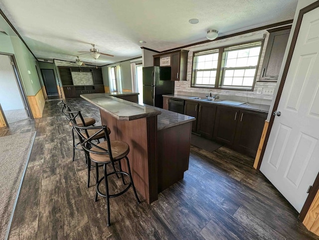 kitchen featuring dark hardwood / wood-style flooring, a center island, a breakfast bar area, and black appliances