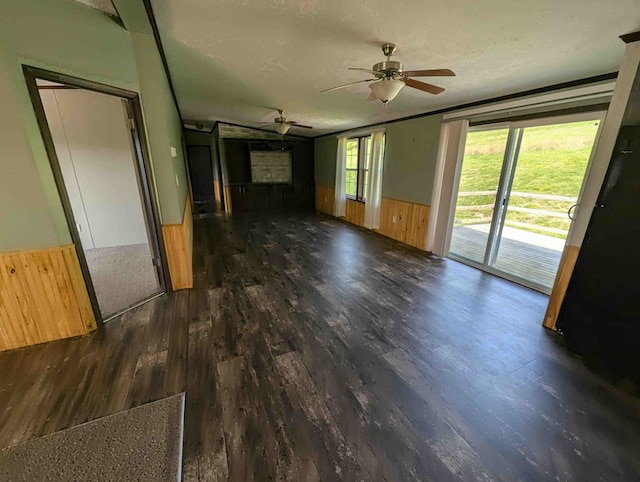 spare room with a textured ceiling, wooden walls, ceiling fan, and dark wood-type flooring