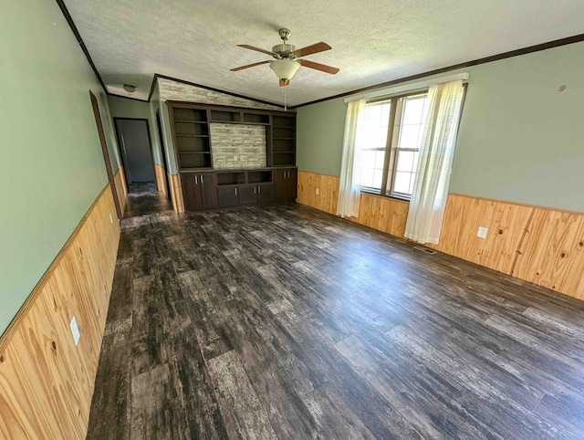 spare room with built in shelves, dark wood-type flooring, a textured ceiling, and ornamental molding