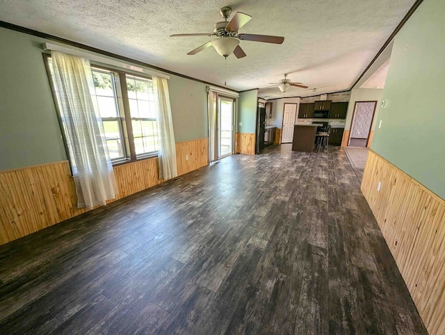 unfurnished living room with wooden walls, dark hardwood / wood-style flooring, and a textured ceiling