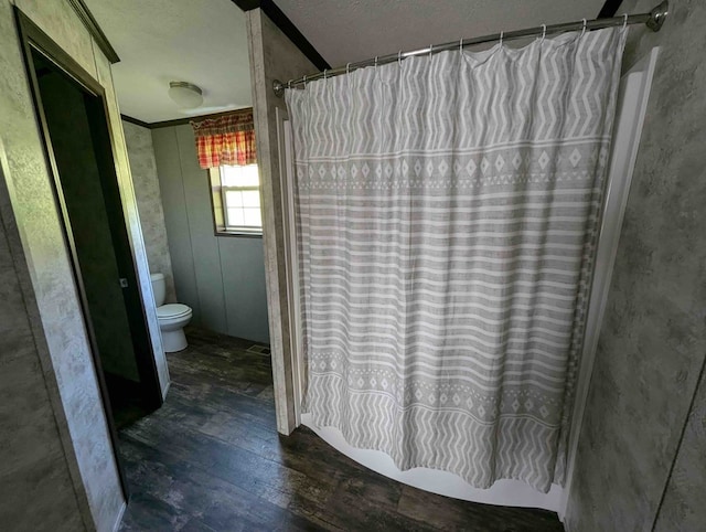 bathroom with a textured ceiling, hardwood / wood-style flooring, toilet, and crown molding