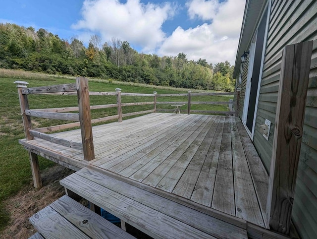 wooden terrace featuring a rural view and a lawn