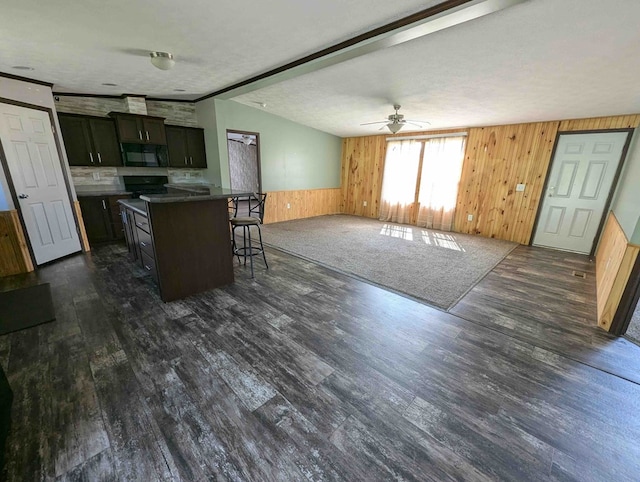 kitchen featuring ceiling fan, dark hardwood / wood-style flooring, a textured ceiling, a breakfast bar area, and a kitchen island