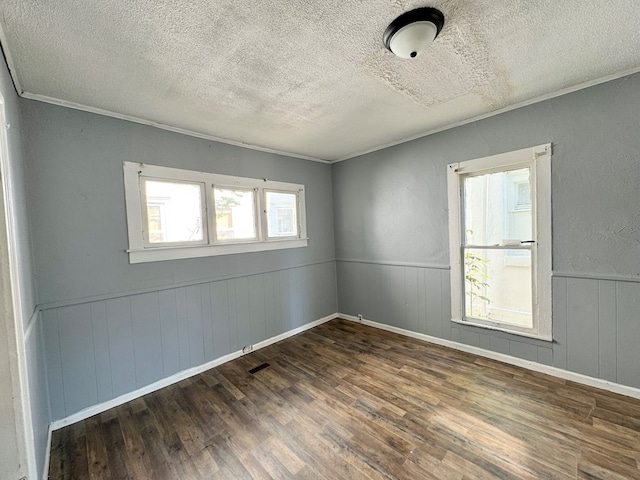 unfurnished room with a textured ceiling, crown molding, and dark wood-type flooring