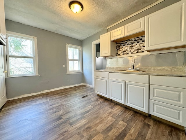 kitchen with dark hardwood / wood-style flooring, tasteful backsplash, a textured ceiling, a healthy amount of sunlight, and white cabinets