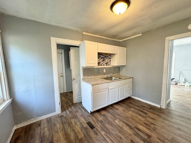 kitchen featuring white cabinets, a textured ceiling, dark wood-type flooring, and sink