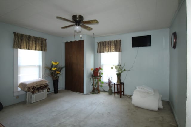 sitting room featuring ceiling fan, plenty of natural light, and light carpet