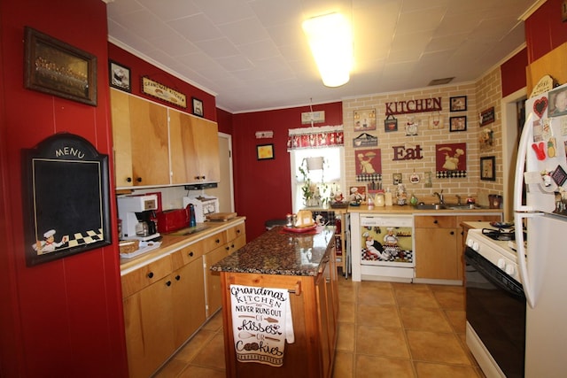 kitchen featuring a kitchen island, dark stone counters, white appliances, light tile patterned floors, and ornamental molding