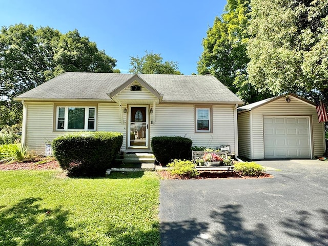 view of front of house with a garage, a front lawn, and an outbuilding