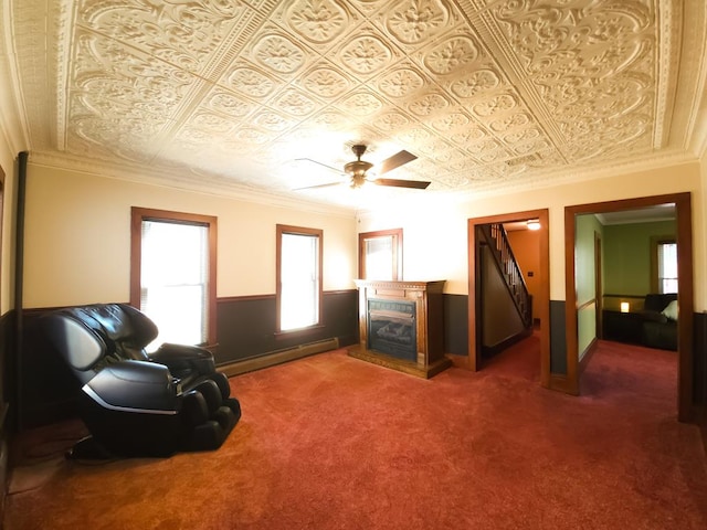 sitting room with carpet flooring, ceiling fan, ornamental molding, a fireplace, and a baseboard radiator