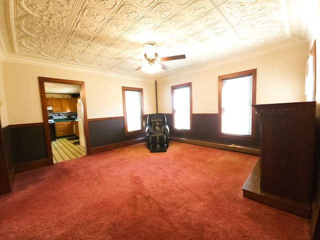 interior space featuring crown molding, carpet, a baseboard heating unit, and ceiling fan