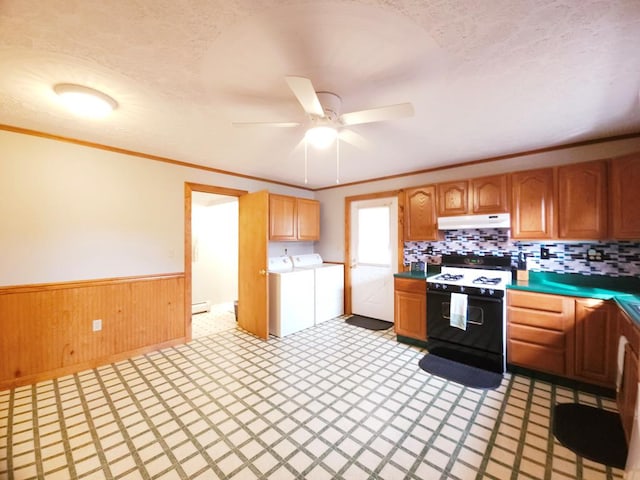 kitchen with electric range, ceiling fan, washing machine and dryer, backsplash, and wood walls