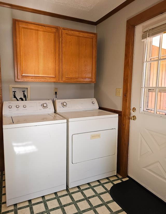 washroom with washing machine and clothes dryer, crown molding, cabinets, and a textured ceiling