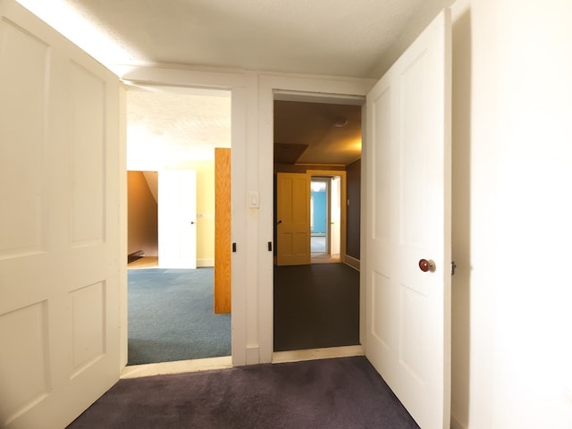 corridor with a textured ceiling and dark carpet