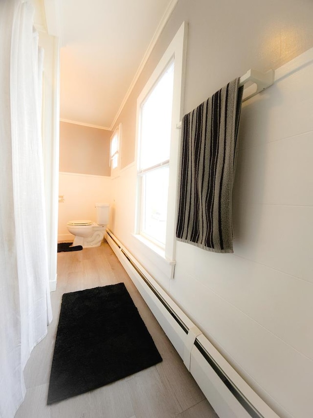 bathroom with crown molding, a baseboard radiator, and toilet