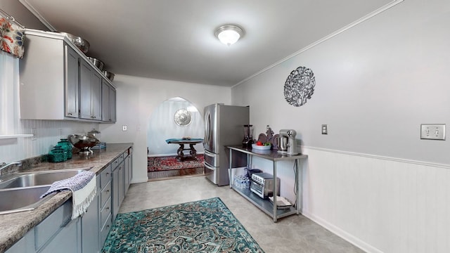 kitchen with stainless steel refrigerator, sink, gray cabinets, and ornamental molding