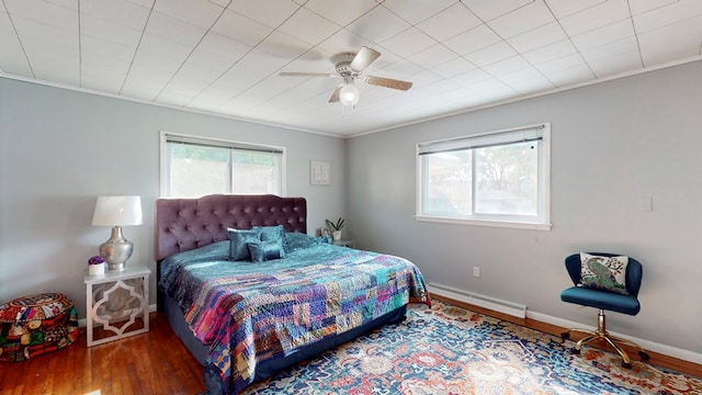 bedroom featuring ornamental molding, dark hardwood / wood-style flooring, ceiling fan, and a baseboard heating unit