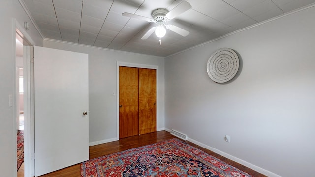 bedroom with a closet, ceiling fan, hardwood / wood-style floors, and ornamental molding