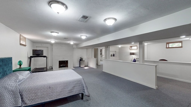 carpeted bedroom with a large fireplace and a textured ceiling