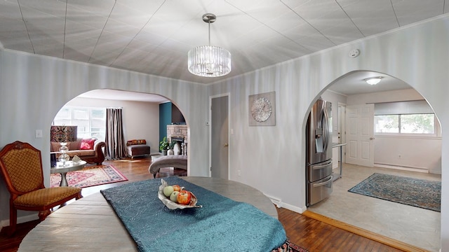 dining area with hardwood / wood-style flooring, a fireplace, a wealth of natural light, and an inviting chandelier