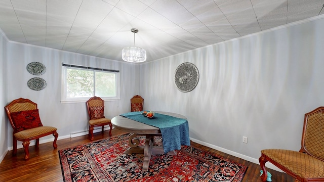 sitting room with a notable chandelier, ornamental molding, dark wood-type flooring, and a baseboard radiator