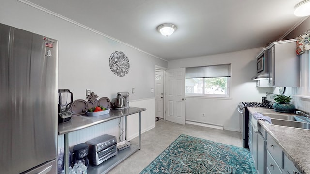 kitchen with appliances with stainless steel finishes, baseboard heating, ornamental molding, and sink