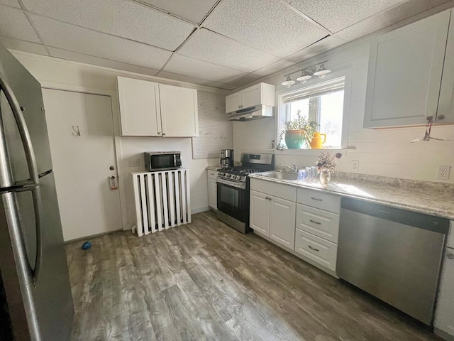 kitchen with wood-type flooring, stainless steel appliances, white cabinets, and a paneled ceiling