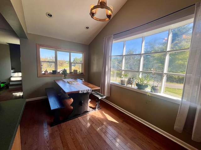 dining space featuring an inviting chandelier, vaulted ceiling, and dark hardwood / wood-style floors