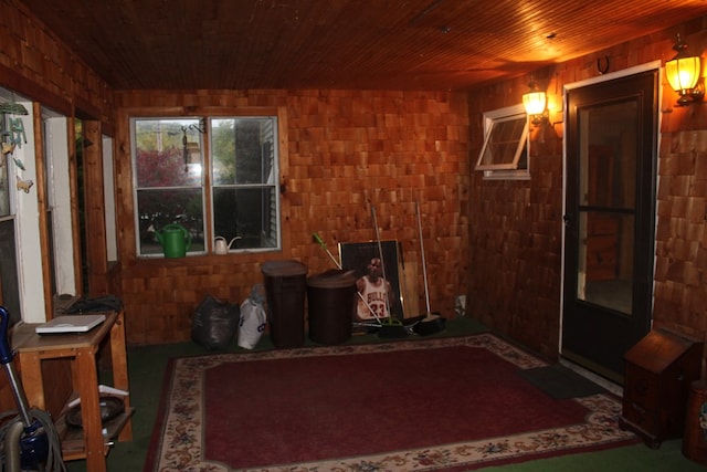 interior space featuring wooden ceiling, wooden walls, and brick wall