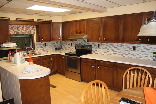 kitchen with sink, tasteful backsplash, kitchen peninsula, appliances with stainless steel finishes, and light wood-type flooring