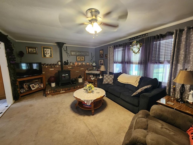 living room featuring a wood stove, ceiling fan, carpet flooring, and crown molding