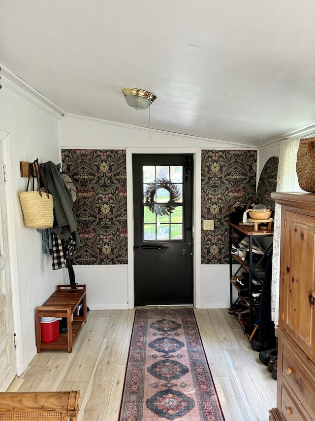 foyer featuring crown molding, lofted ceiling, and light wood-type flooring