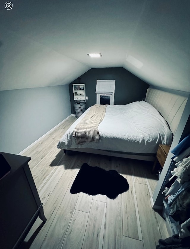 bedroom featuring light hardwood / wood-style floors and vaulted ceiling