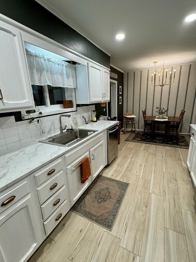 kitchen with dishwasher, backsplash, white cabinets, sink, and light stone countertops