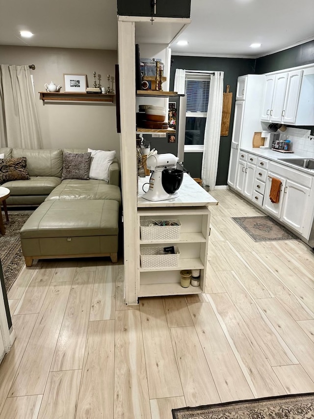 interior space with white cabinets, sink, and light hardwood / wood-style flooring