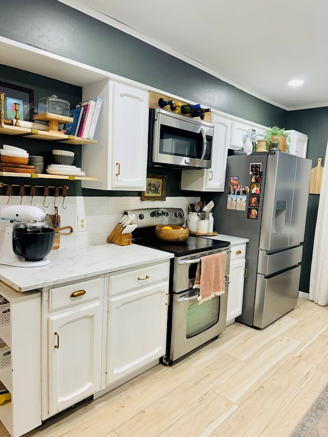 kitchen featuring backsplash, white cabinetry, stainless steel appliances, and light hardwood / wood-style flooring