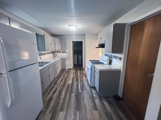 kitchen featuring backsplash, white appliances, dark hardwood / wood-style floors, and independent washer and dryer