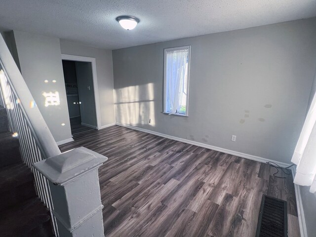 spare room with dark wood-type flooring and a textured ceiling