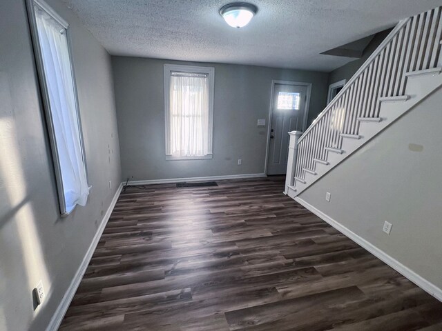 entryway featuring dark wood-type flooring and a textured ceiling