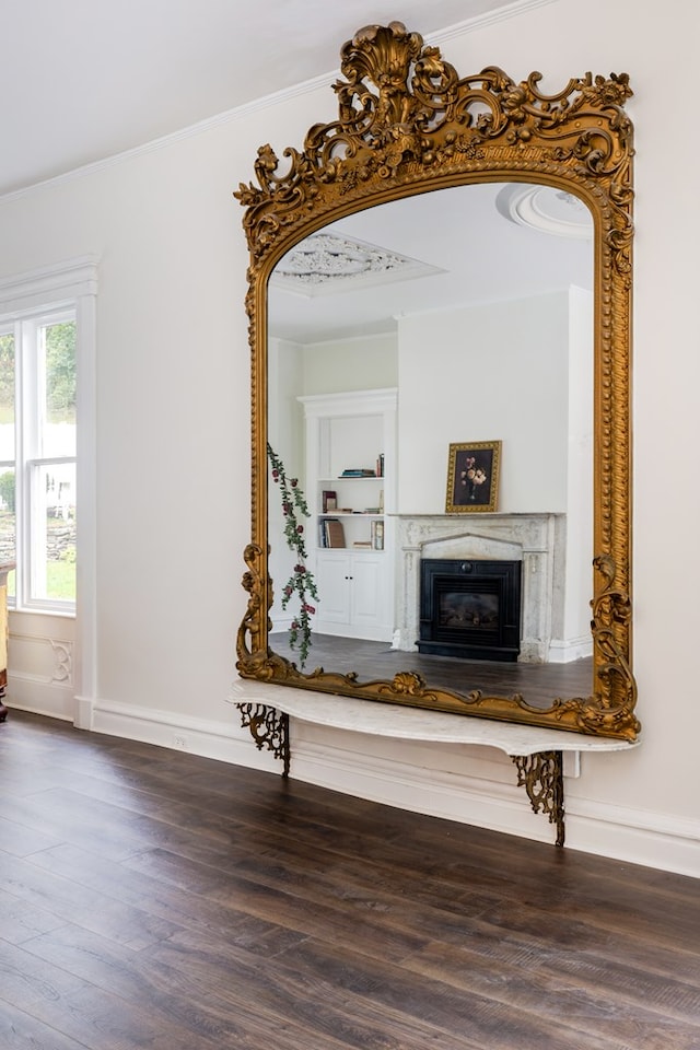 corridor with dark hardwood / wood-style flooring, built in features, and crown molding