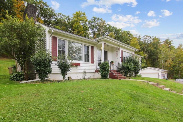 ranch-style house featuring a garage, an outbuilding, and a front lawn