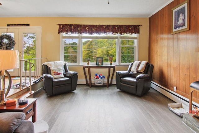 sitting room featuring hardwood / wood-style flooring, baseboard heating, crown molding, and wood walls