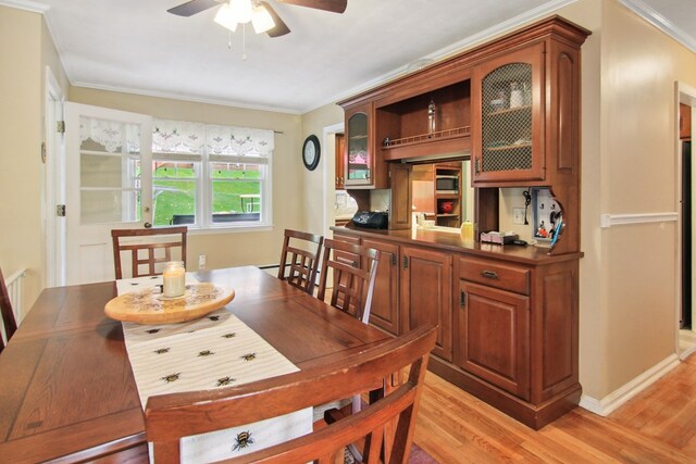 dining room with ceiling fan, light wood-type flooring, and crown molding