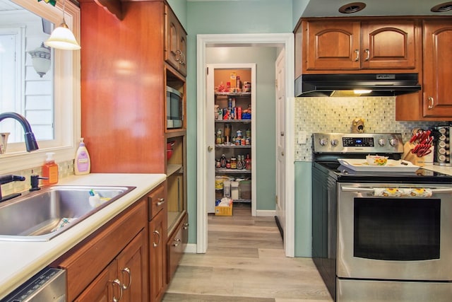 kitchen featuring pendant lighting, sink, decorative backsplash, light hardwood / wood-style floors, and stainless steel appliances