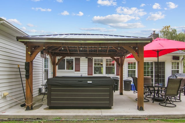 back of property featuring a gazebo, a patio, and a hot tub