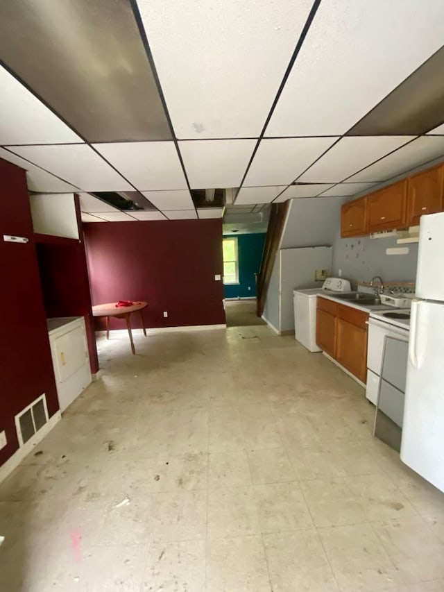 kitchen with a paneled ceiling, white appliances, sink, and washer / clothes dryer