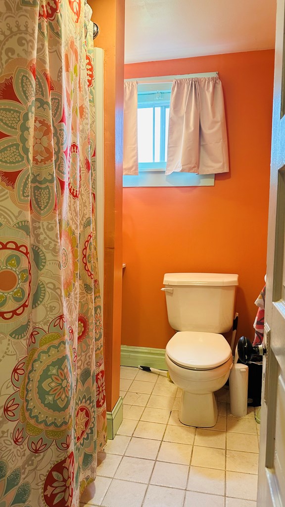 bathroom with a shower with curtain, toilet, and tile patterned floors