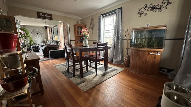 dining area featuring wood-type flooring and crown molding