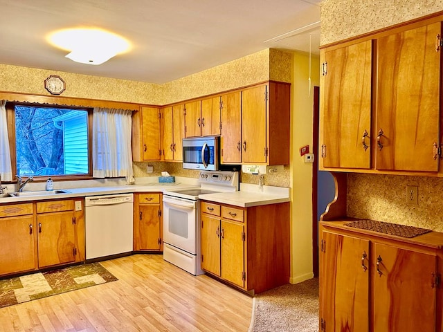 kitchen with sink, white appliances, and light wood-type flooring