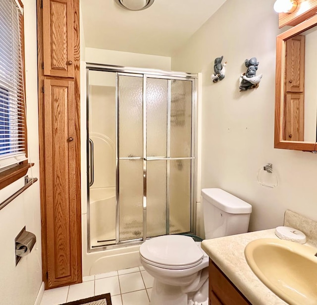 bathroom featuring tile patterned flooring, vanity, an enclosed shower, and toilet